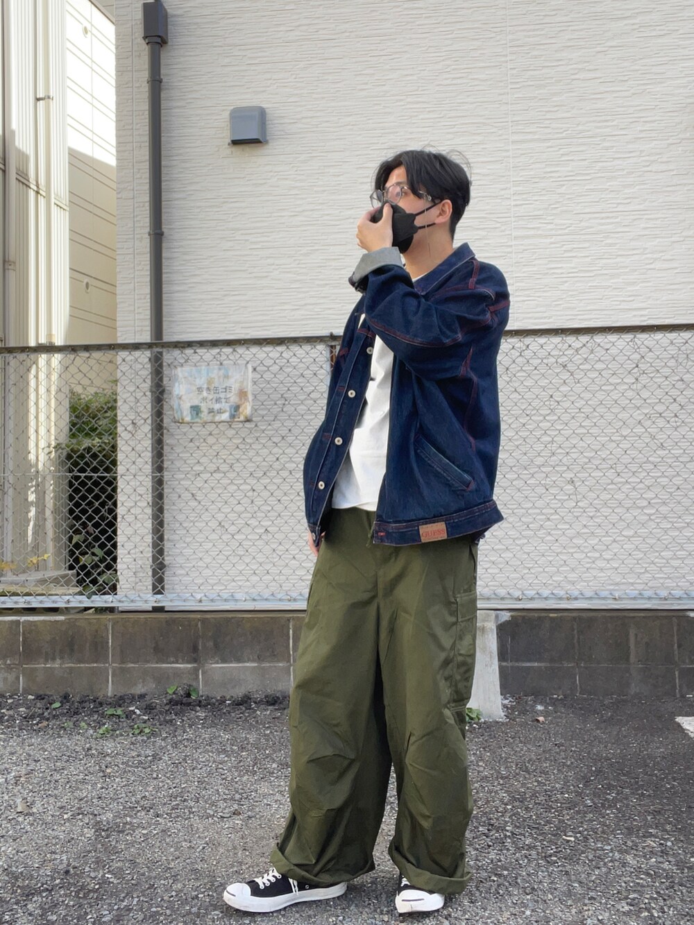 ベージュ系のトートバッグ、ブルー系のデニムジャケット、グリーン系のパンツを着用したメンズの秋コーディネートの3枚目の写真