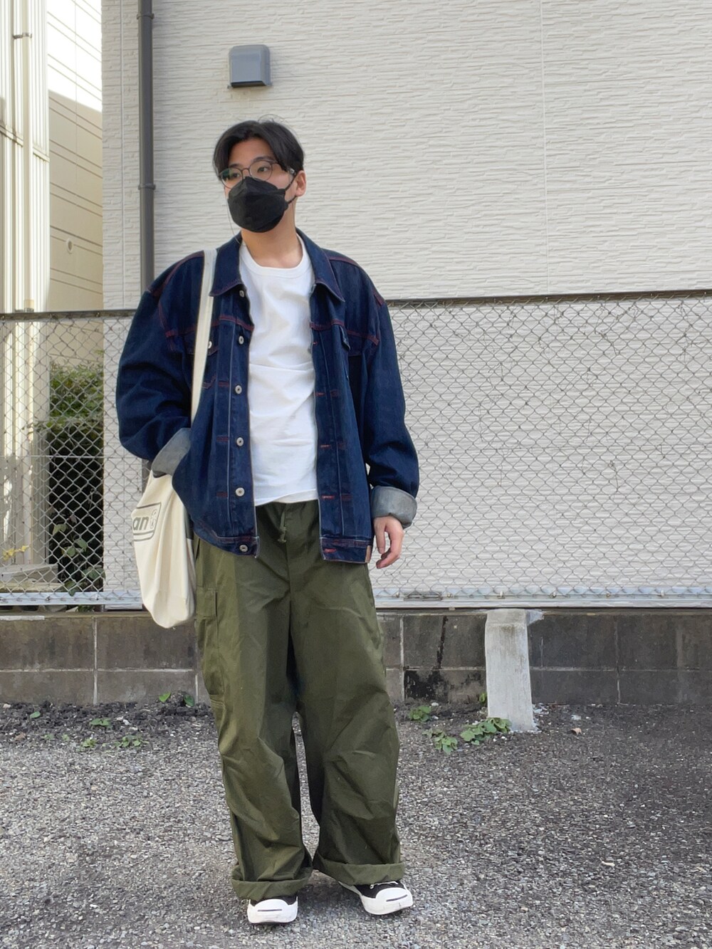 ベージュ系のトートバッグ、ブルー系のデニムジャケット、グリーン系のパンツを着用したメンズの秋コーディネートの2枚目の写真