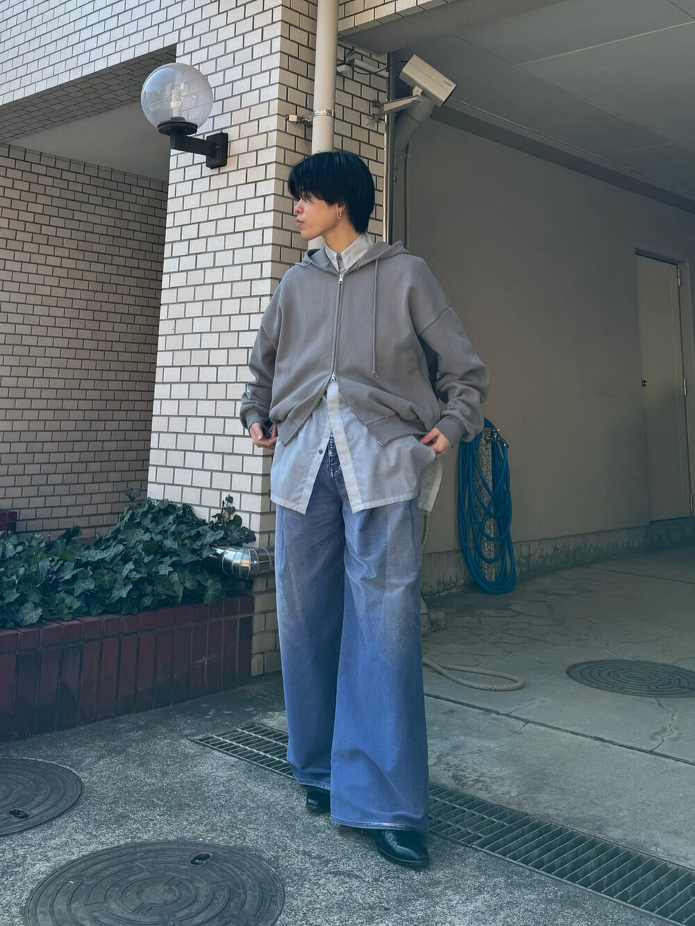 グレー系のパーカー、ブルー系のデニムパンツ、ブラック系のブーツを着用したメンズの秋コーディネートの2枚目の写真