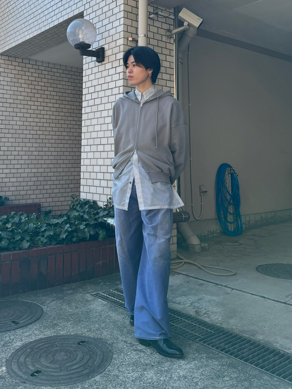 グレー系のパーカー、ブルー系のデニムパンツ、ブラック系のブーツを着用したメンズの秋コーディネートの4枚目の写真