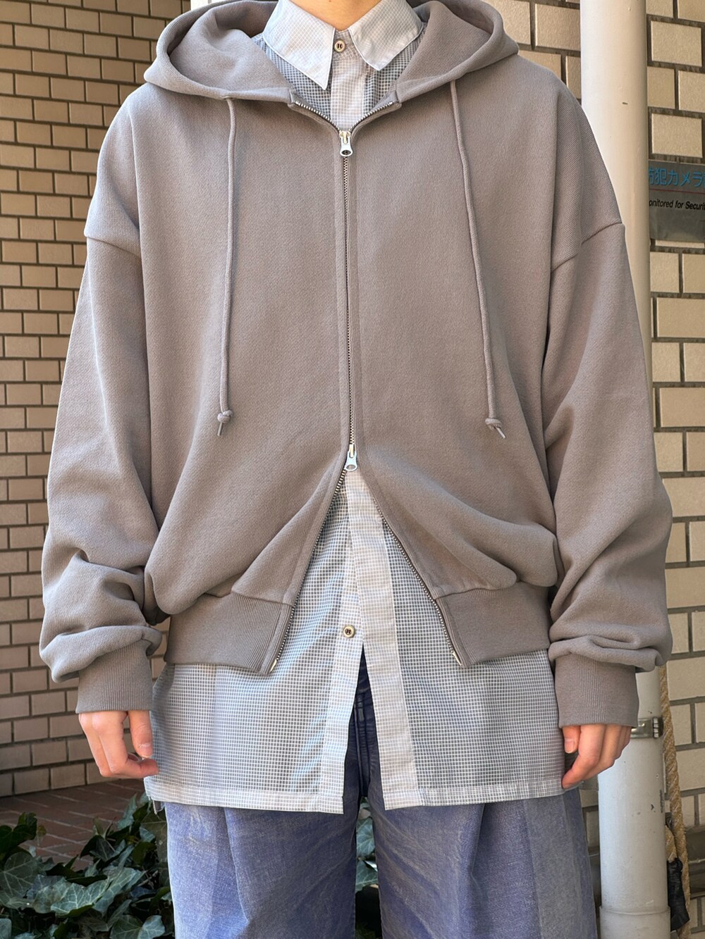 グレー系のパーカー、ブルー系のデニムパンツ、ブラック系のブーツを着用したメンズの秋コーディネートの3枚目の写真