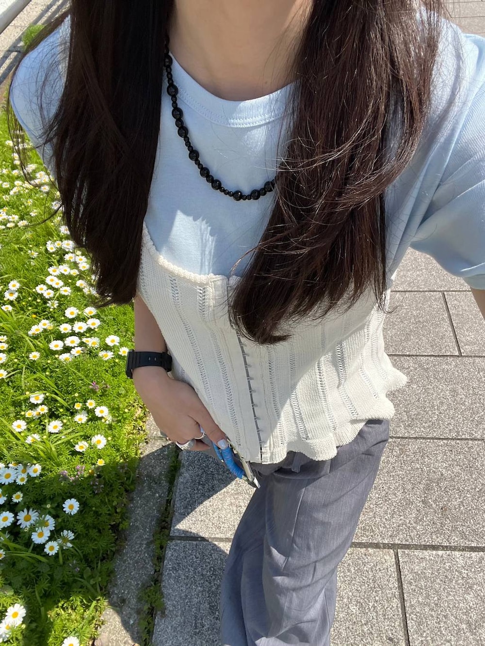 ブラック系のボストンバッグ、ベージュ系のパンプス、グレー系のベストを着用したレディースの春コーディネートの5枚目の写真