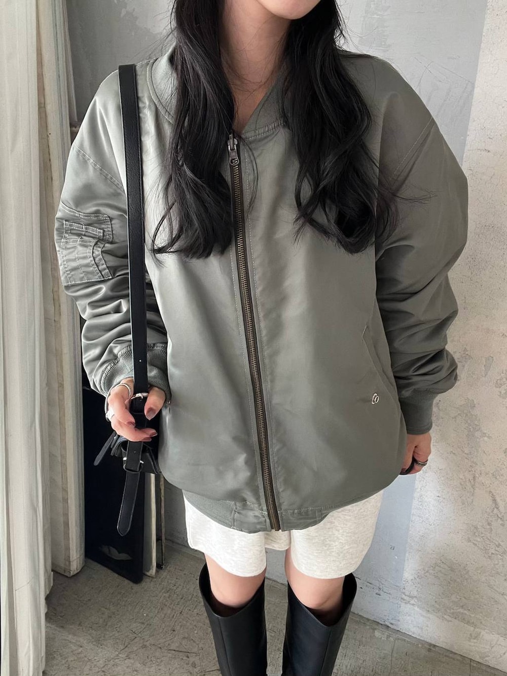 ブラック系のショルダーバッグ、グレー系のスウェットパンツ、ブラック系のブーツを着用したレディースの秋コーディネートの3枚目の写真