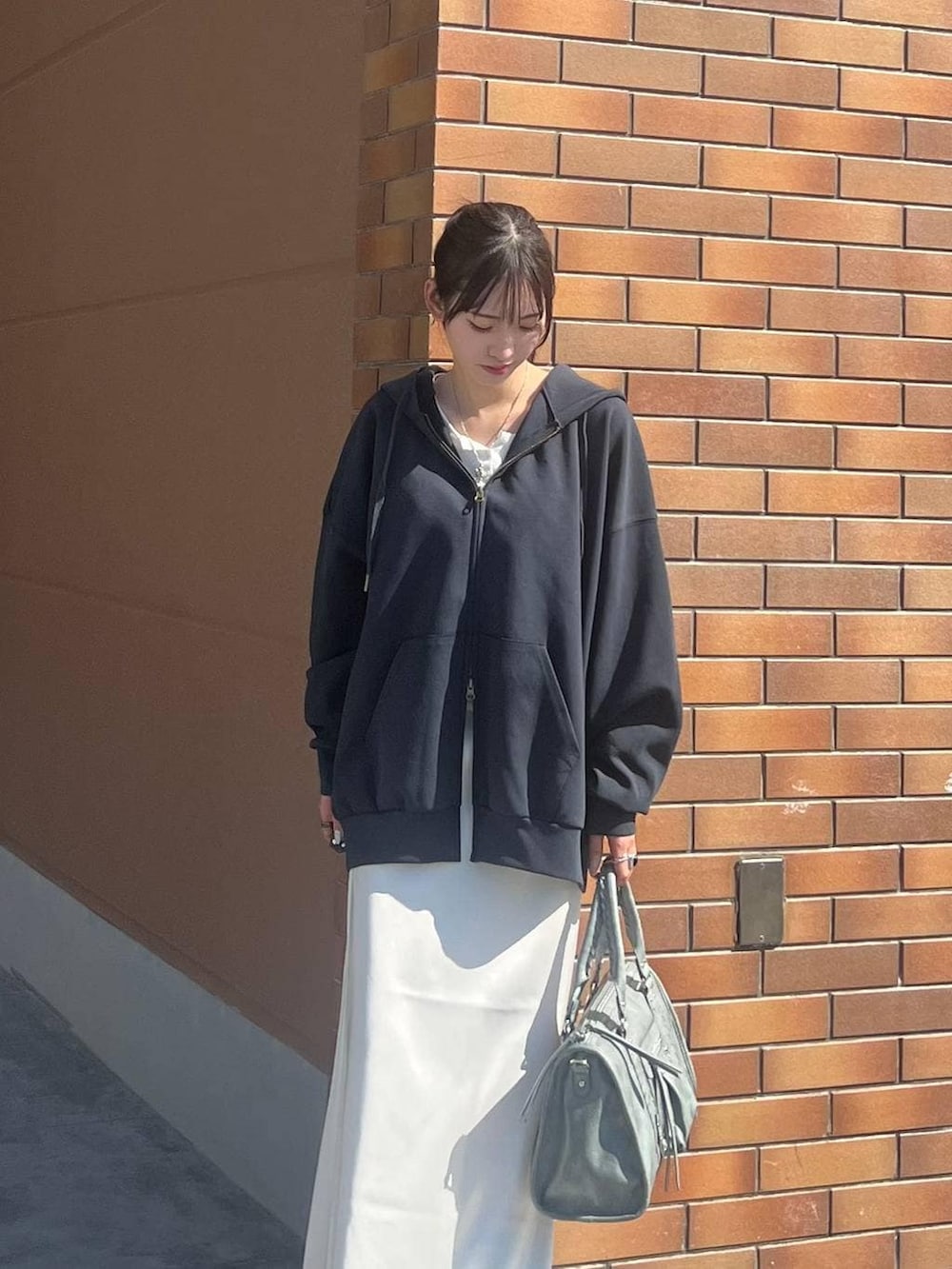 ホワイト系のTシャツ/カットソー、ブラック系のスニーカー、ホワイト系のスカートを着用したレディースの春コーディネートの2枚目の写真