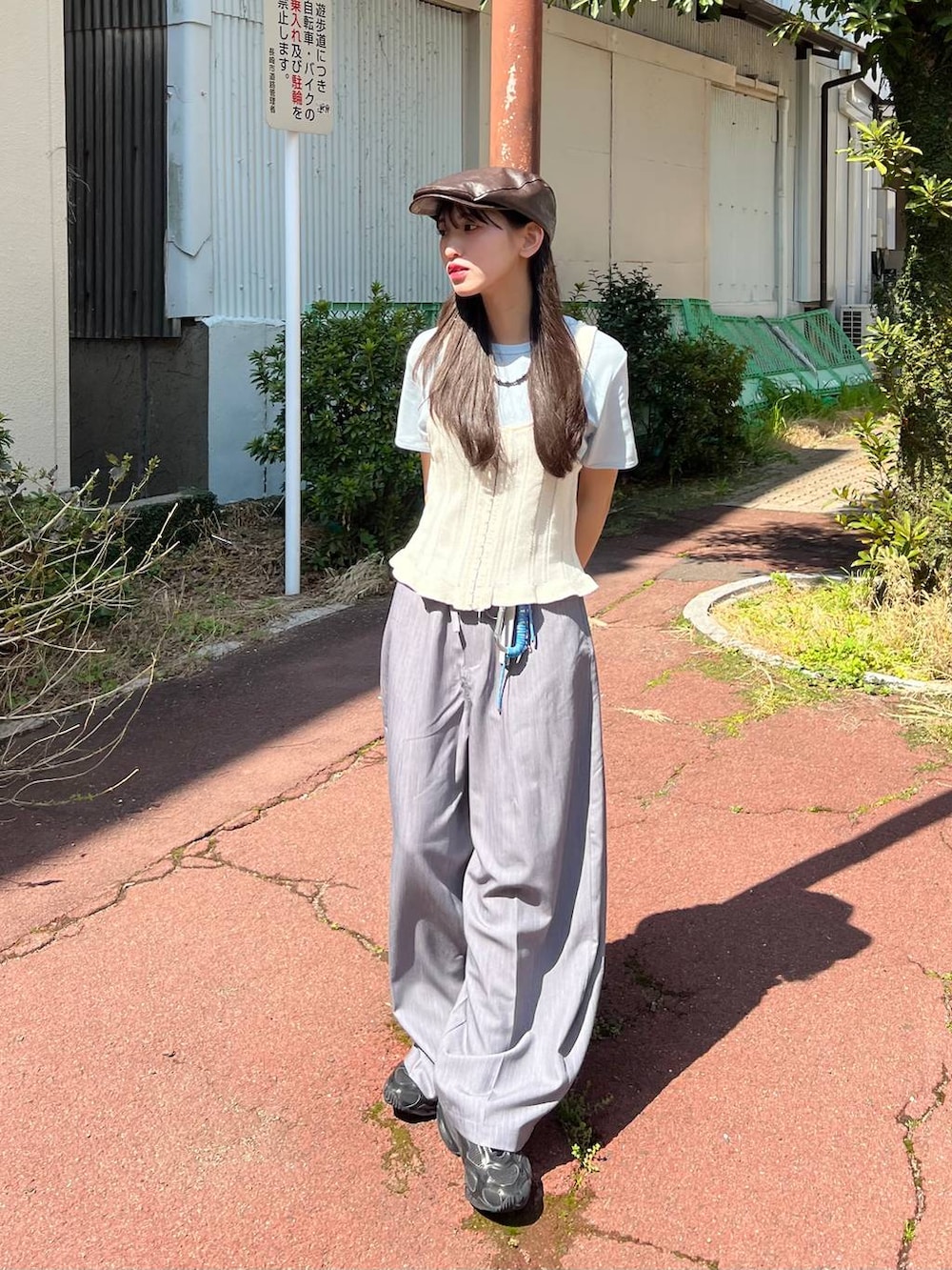 ブラック系のボストンバッグ、ベージュ系のパンプス、グレー系のベストを着用したレディースの春コーディネートの3枚目の写真