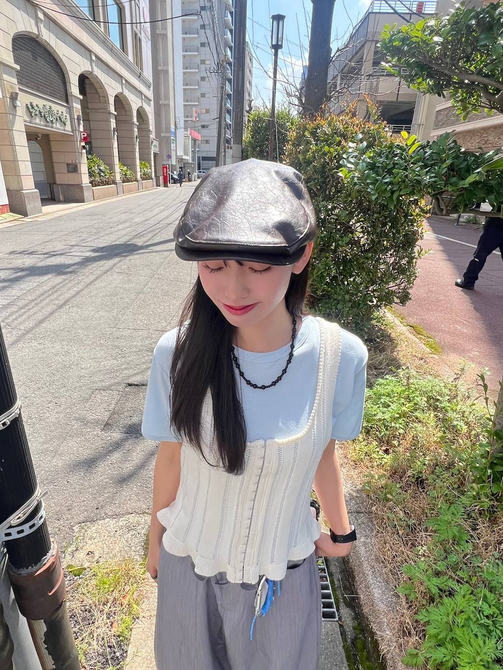 ブラック系のボストンバッグ、ベージュ系のパンプス、グレー系のベストを着用したレディースの春コーディネートの4枚目の写真