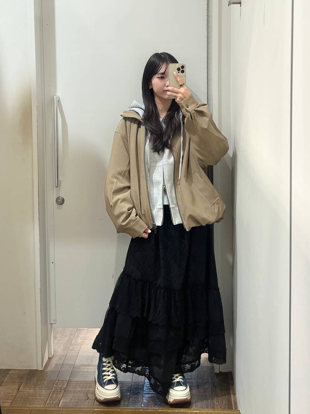 ブルー系のスニーカー、グレー系のパーカー、ブラック系のスカートを着用したレディースの春コーディネートの2枚目の写真