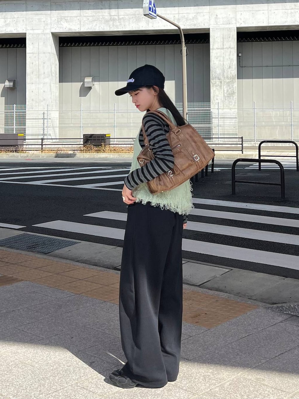 ブラック系のTシャツ/カットソー、ブラック系のスウェットパンツ、ブラウン系のボストンバッグを着用したレディースの冬コーディネートの4枚目の写真