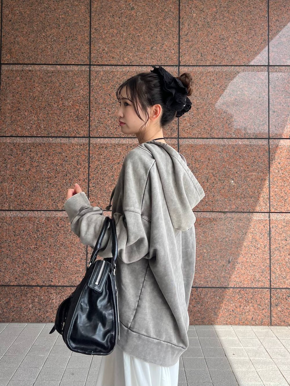 グレー系のパーカー、ブラック系のボストンバッグ、ブラック系のブーツを着用したレディースの夏コーディネートの4枚目の写真