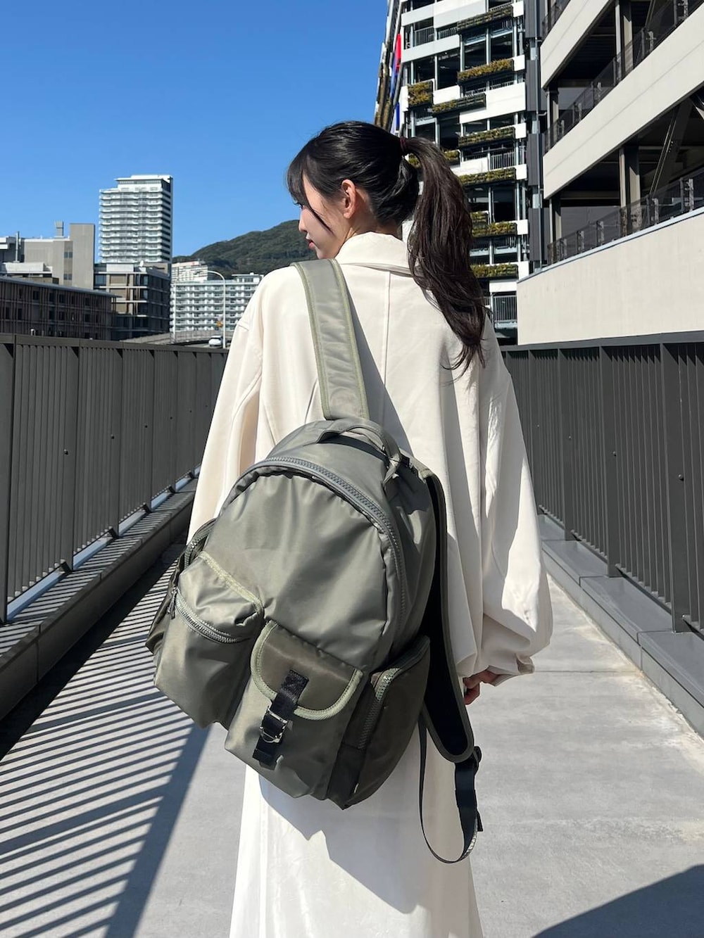 ブラック系のスニーカー、グリーン系のバックパック/リュック、ホワイト系のスカートを着用したレディースの春コーディネートの4枚目の写真