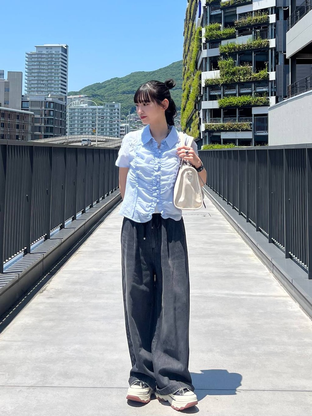 ブラック系のスニーカー、ホワイト系のボストンバッグ、ブラック系のデニムパンツを着用したレディースの夏コーディネートの2枚目の写真