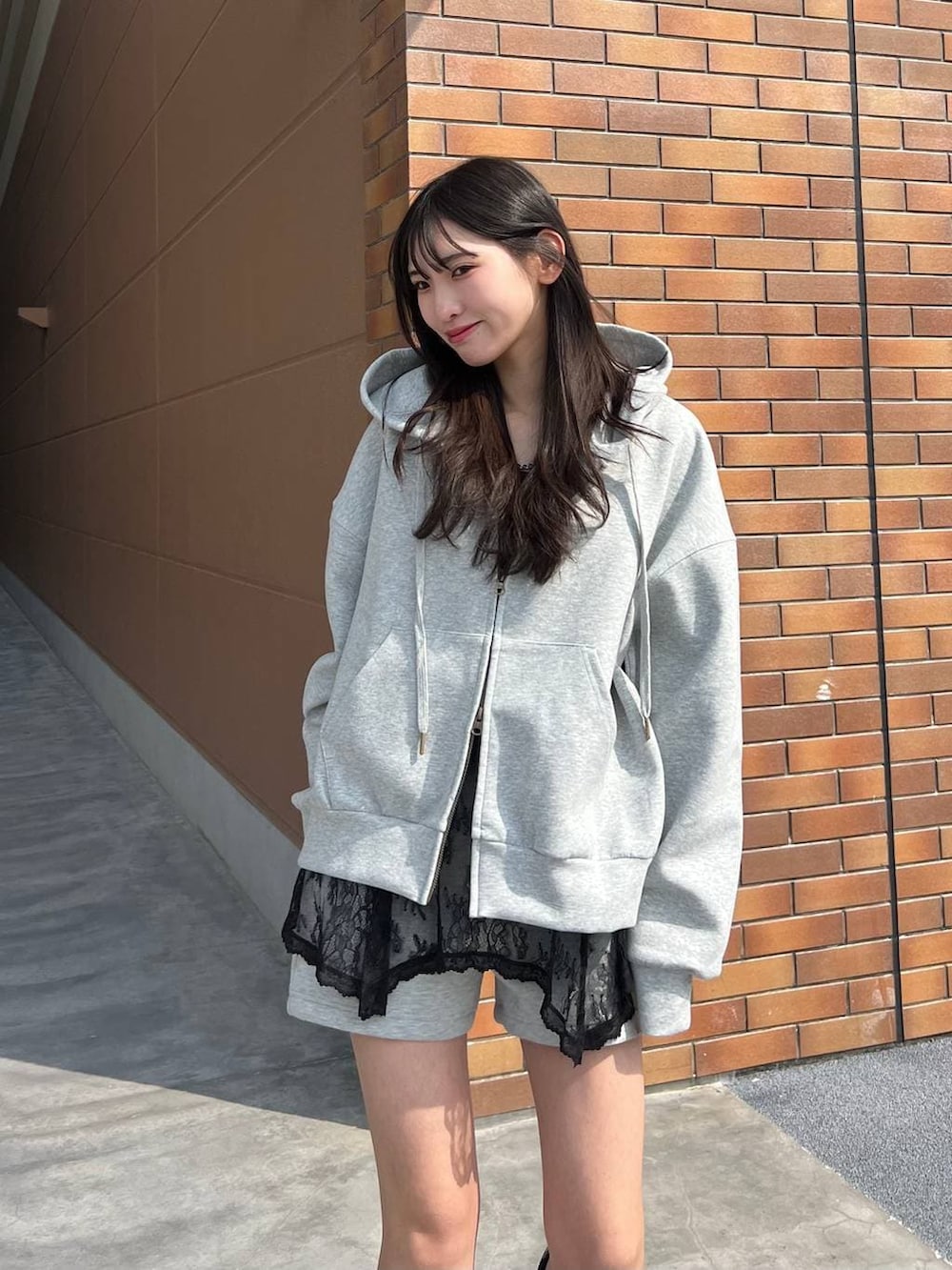 ブラック系のブーツ、グレー系のスウェットパンツ、グレー系のパーカーを着用したレディースの春コーディネートの2枚目の写真