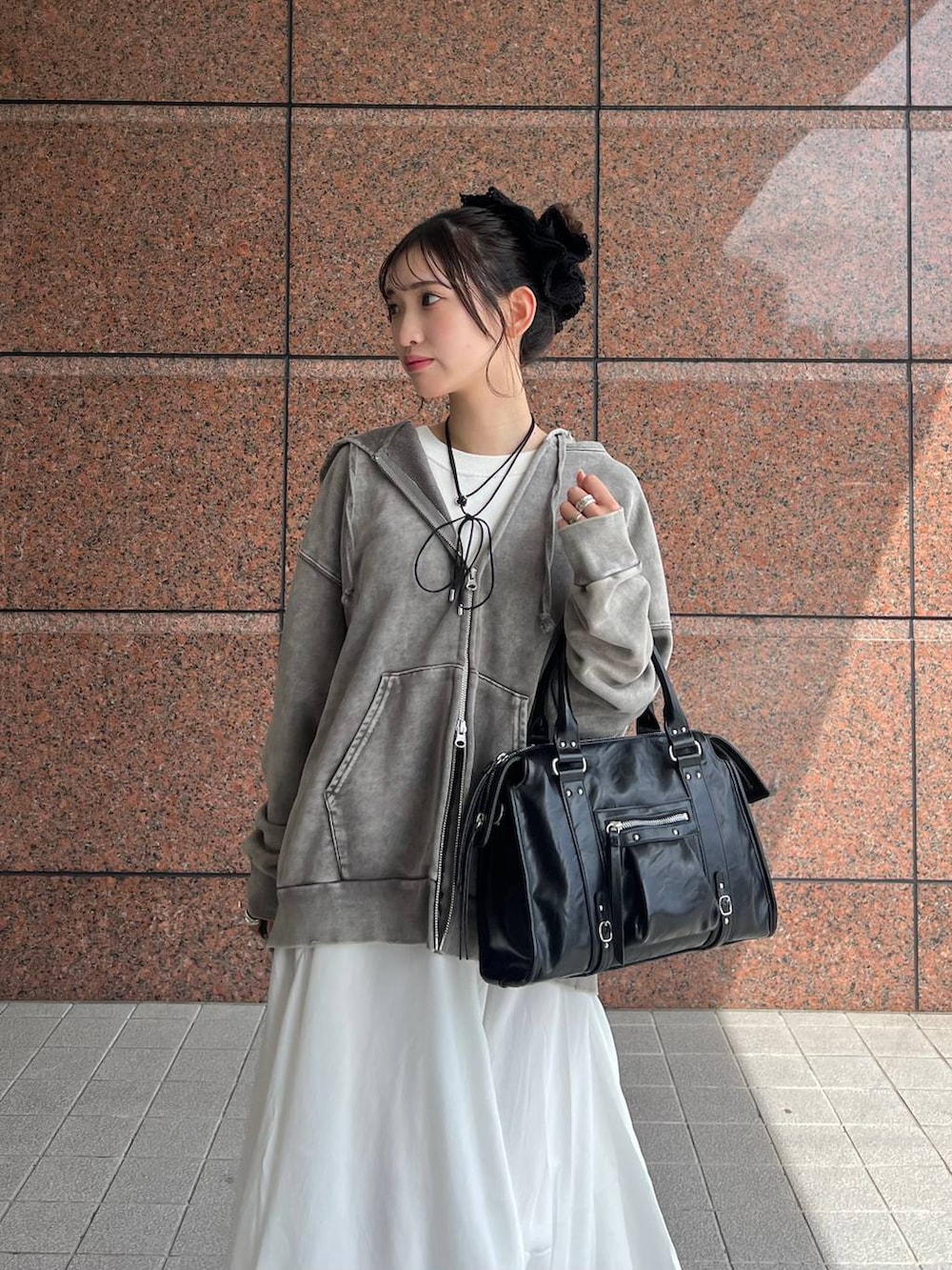 グレー系のパーカー、ブラック系のボストンバッグ、ブラック系のブーツを着用したレディースの夏コーディネートの3枚目の写真