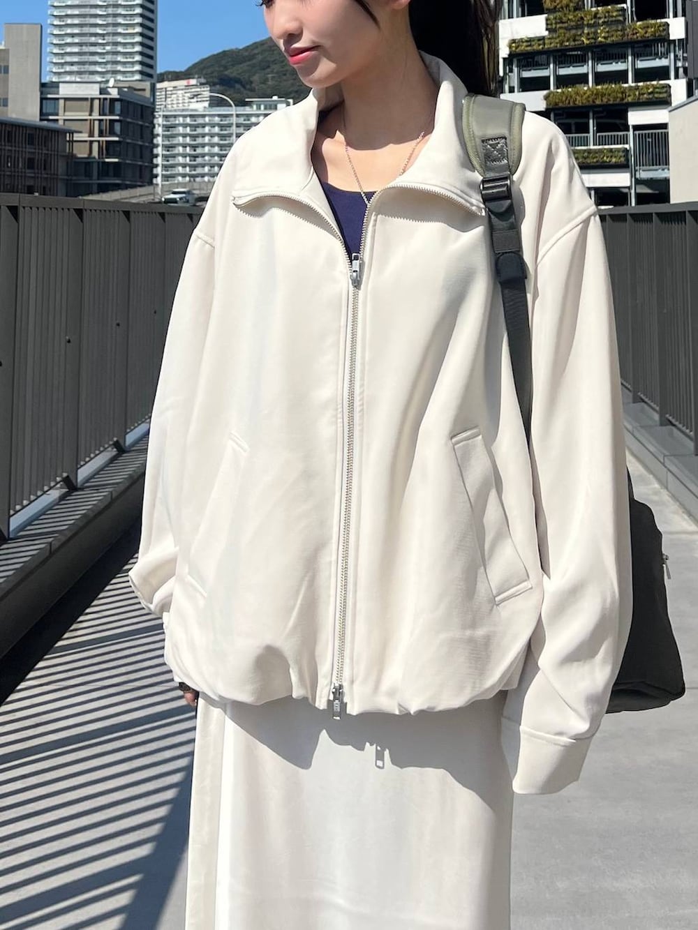 ブラック系のスニーカー、グリーン系のバックパック/リュック、ホワイト系のスカートを着用したレディースの春コーディネートの3枚目の写真