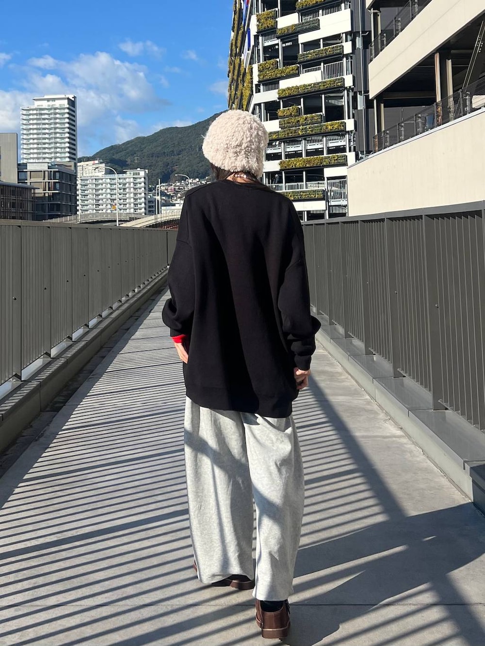 ブラック系のニット/セーター、ブラウン系のその他シューズ、グレー系のスウェットパンツを着用したレディースの冬コーディネートの4枚目の写真