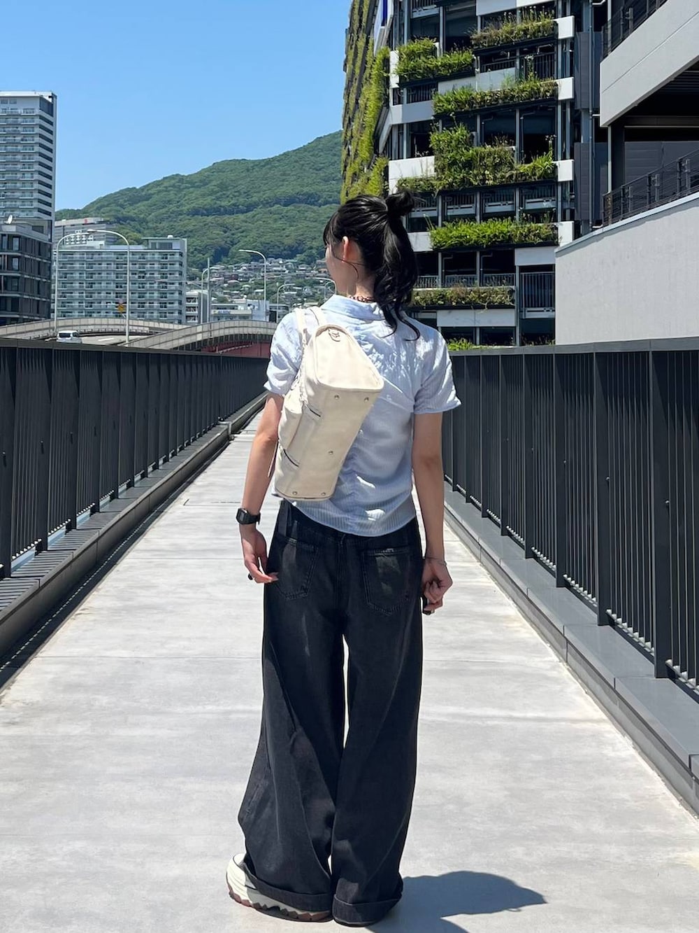 ブラック系のスニーカー、ホワイト系のボストンバッグ、ブラック系のデニムパンツを着用したレディースの夏コーディネートの4枚目の写真