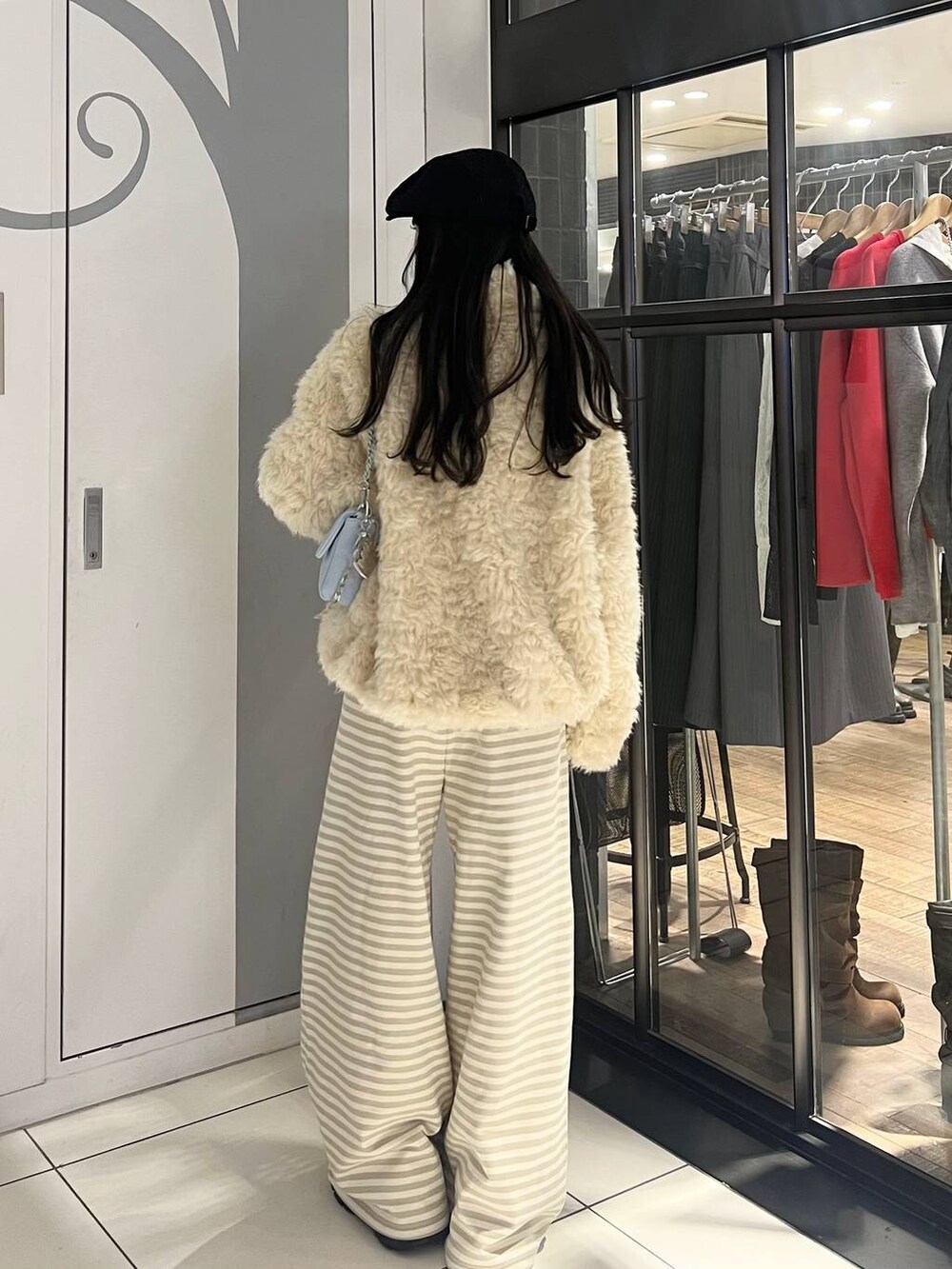 ホワイト系のブルゾン、ベージュ系のスウェットパンツ、ブルー系のショルダーバッグを着用したレディースの秋コーディネートの4枚目の写真
