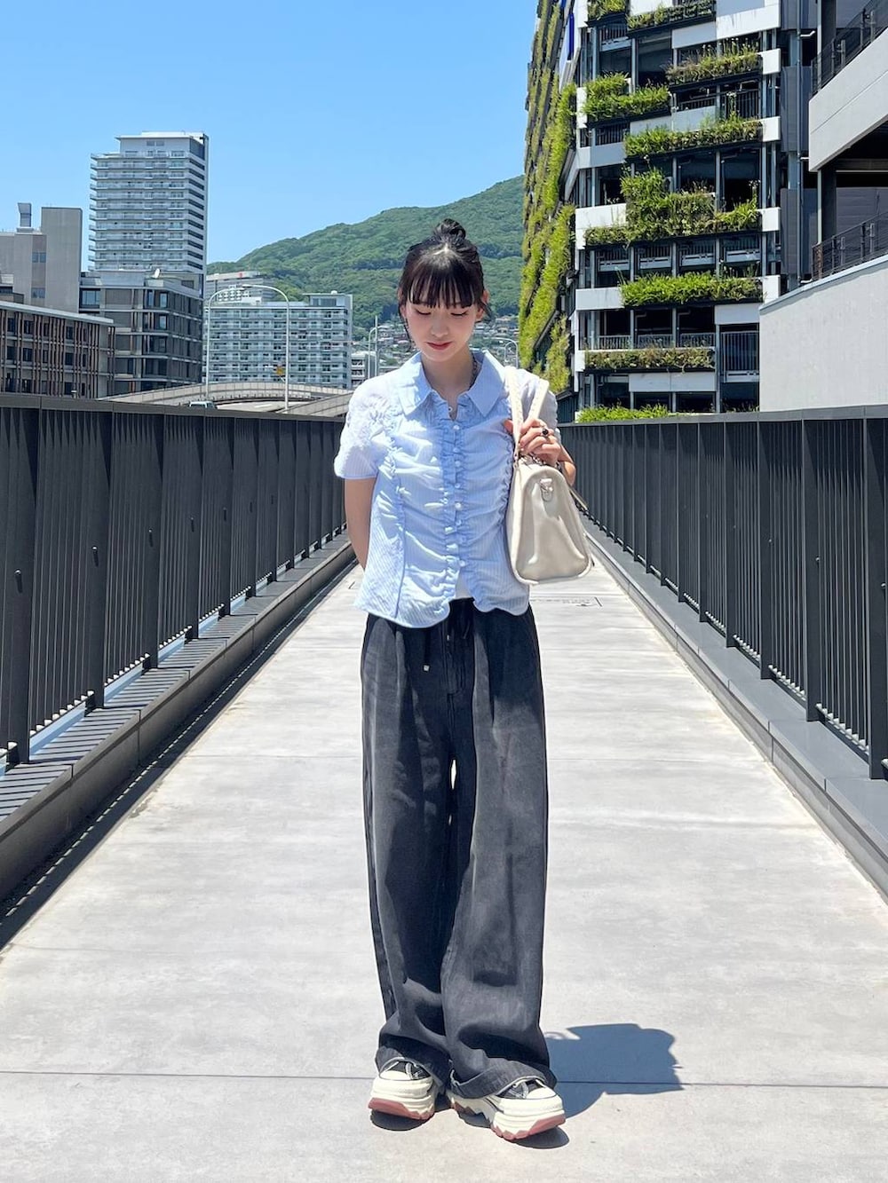 ブラック系のスニーカー、ホワイト系のボストンバッグ、ブラック系のデニムパンツを着用したレディースの夏コーディネートの6枚目の写真