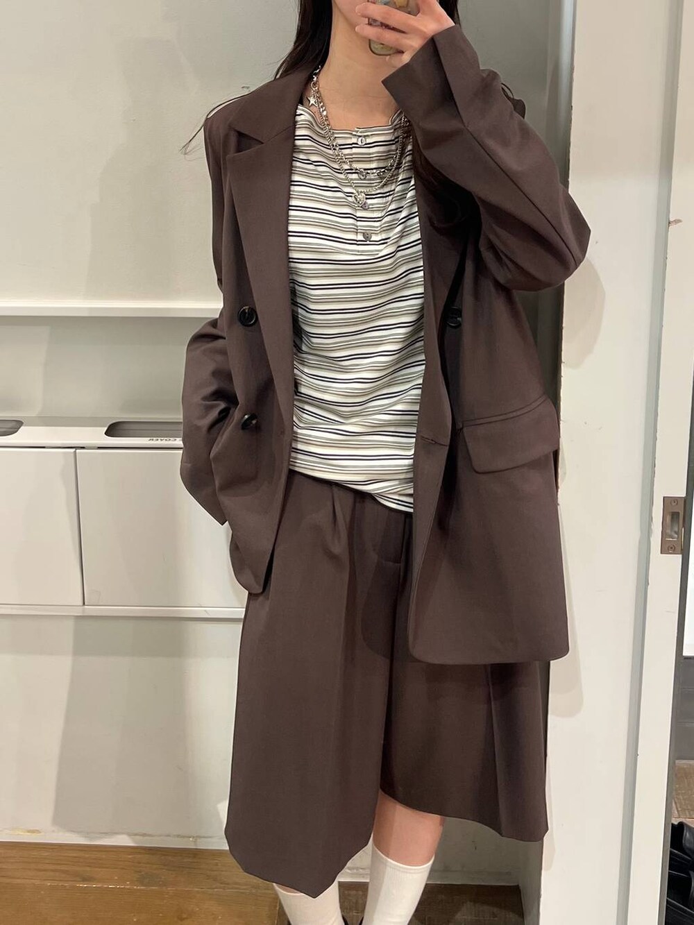 ホワイト系のTシャツ/カットソー、ブラウン系のテーラードジャケット、ブラック系のパンプスを着用したレディースの冬コーディネートの7枚目の写真