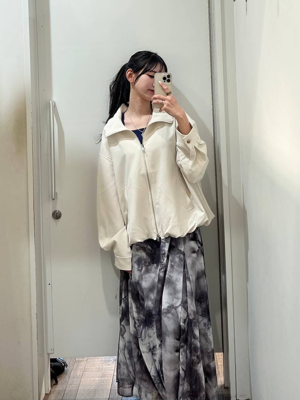 ブラック系のスニーカー、ブルー系のタンクトップ、ホワイト系のブルゾンを着用したレディースの春コーディネートの3枚目の写真