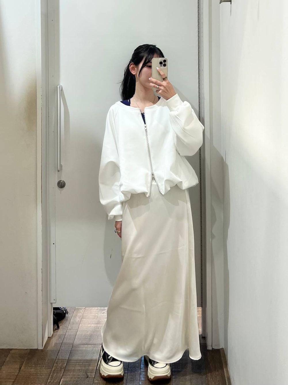 ホワイト系のスウェット、ブラック系のスニーカー、ホワイト系のスカートを着用したレディースの春コーディネートの3枚目の写真