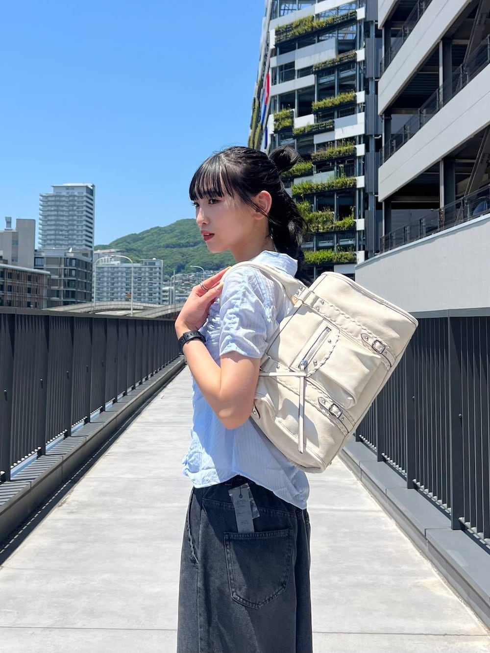 ブラック系のスニーカー、ホワイト系のボストンバッグ、ブラック系のデニムパンツを着用したレディースの夏コーディネートの5枚目の写真