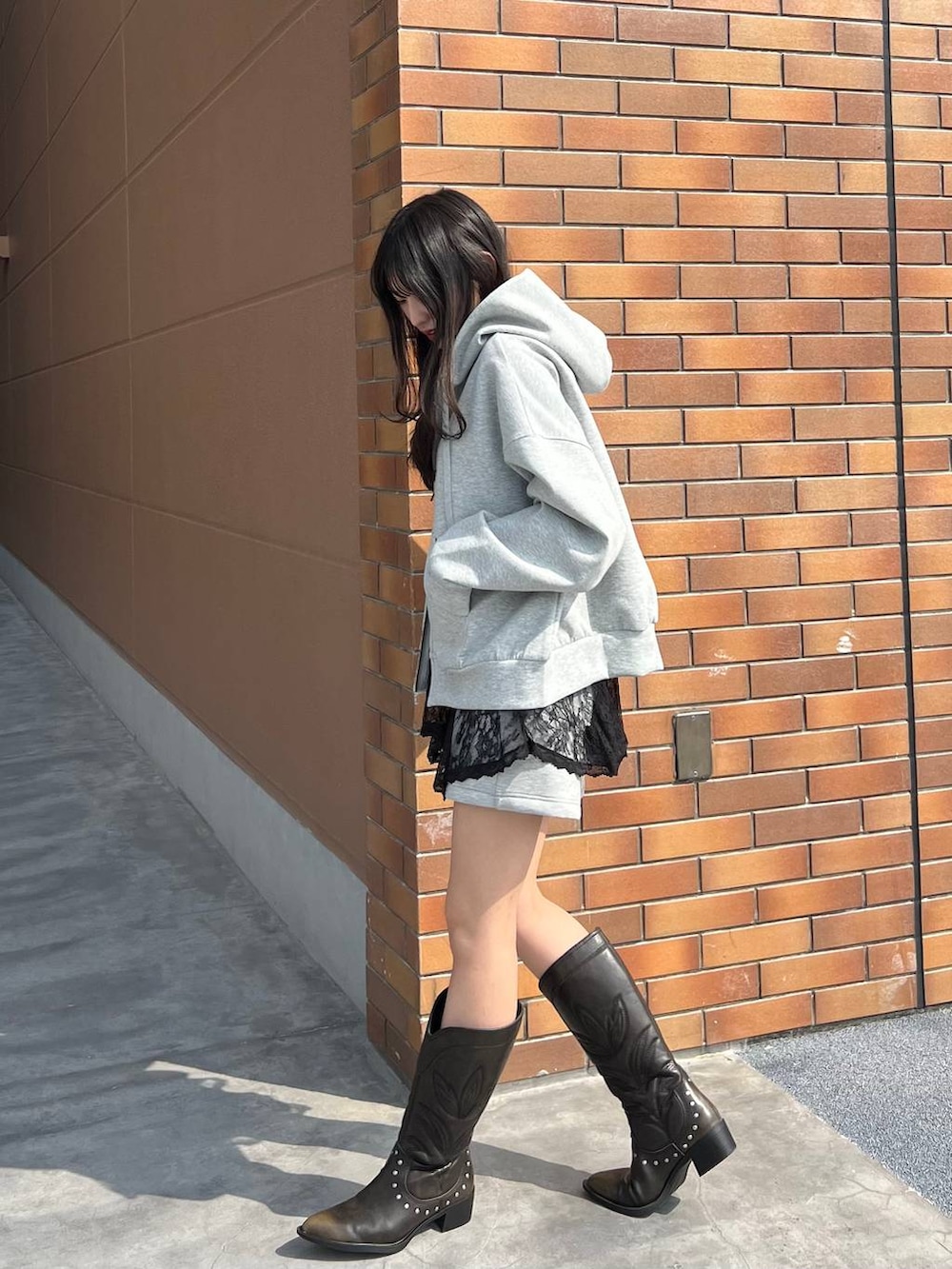 ブラック系のブーツ、グレー系のスウェットパンツ、グレー系のパーカーを着用したレディースの春コーディネートの3枚目の写真