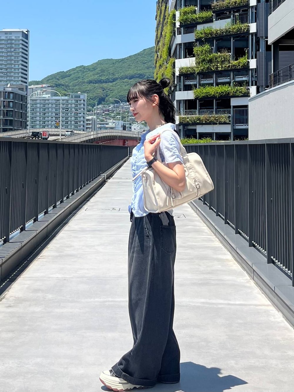 ブラック系のスニーカー、ホワイト系のボストンバッグ、ブラック系のデニムパンツを着用したレディースの夏コーディネートの3枚目の写真