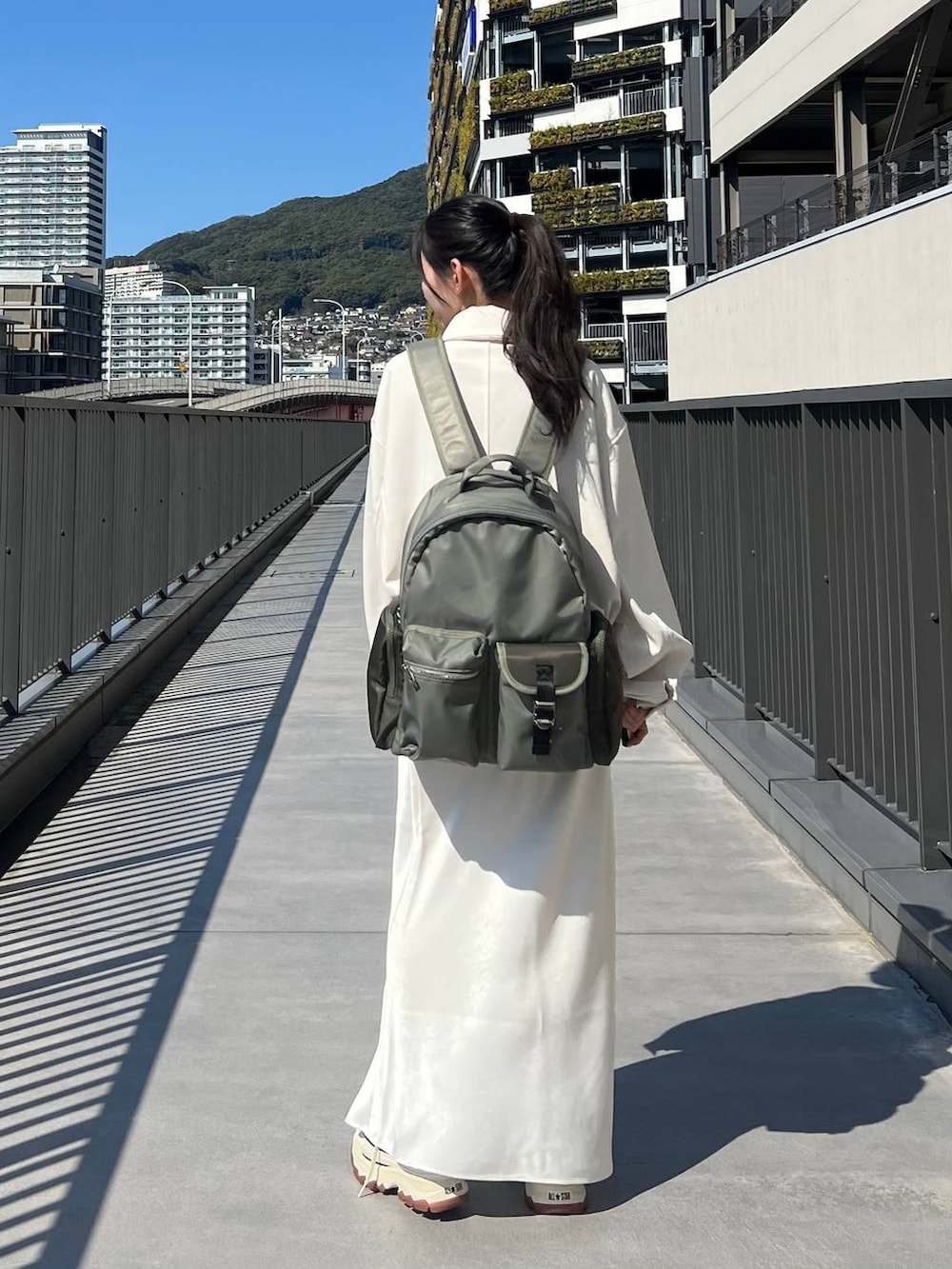 ブラック系のスニーカー、グリーン系のバックパック/リュック、ホワイト系のスカートを着用したレディースの春コーディネートの6枚目の写真