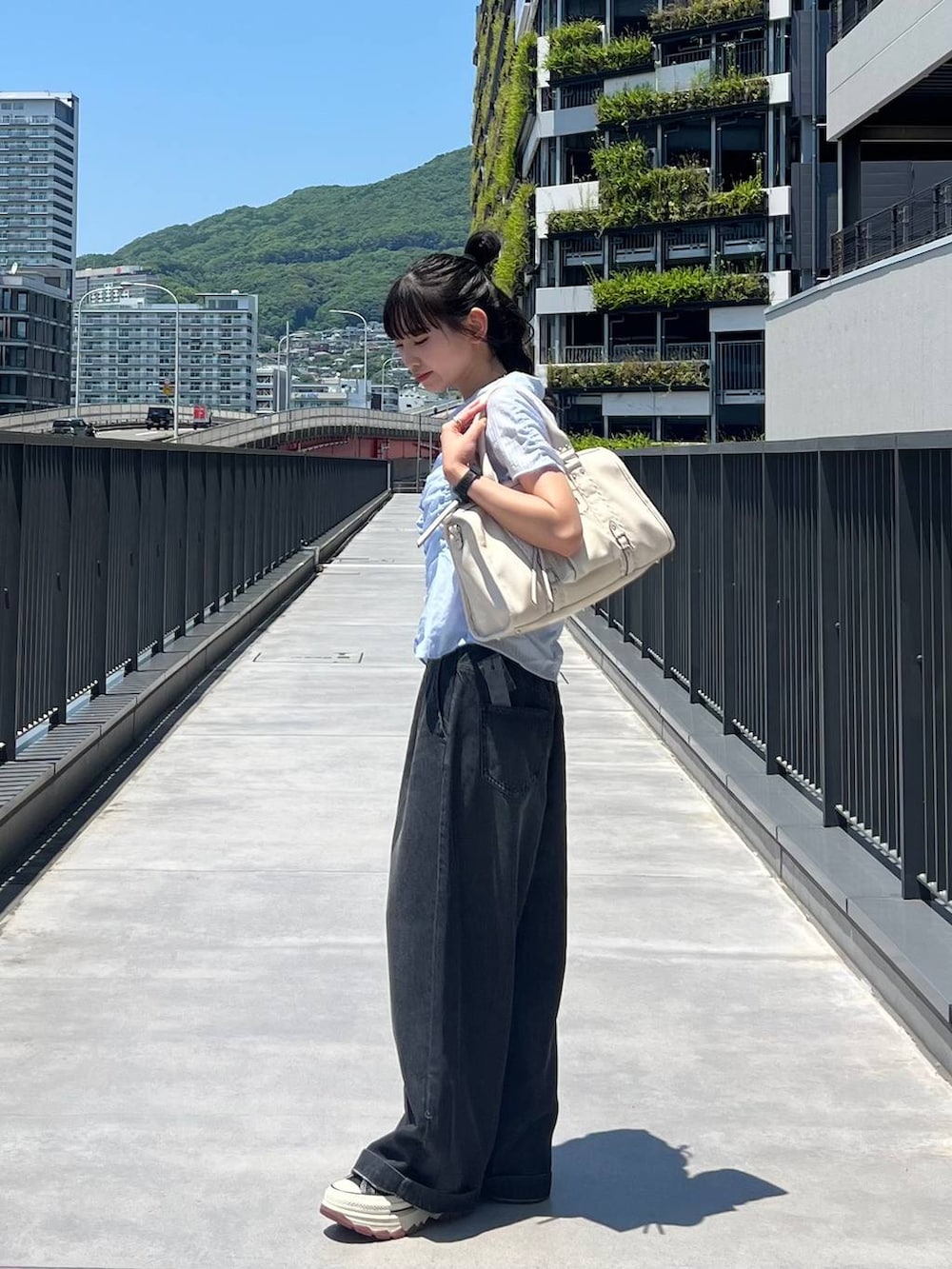 ブラック系のスニーカー、ホワイト系のボストンバッグ、ブラック系のデニムパンツを着用したレディースの夏コーディネートの7枚目の写真