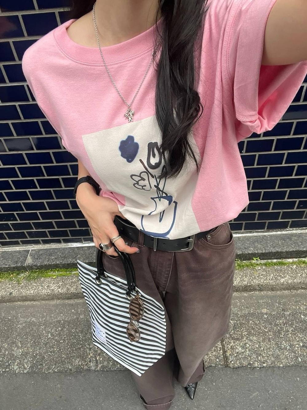 ピンク系のTシャツ/カットソー、ブラック系のパンプス、ブラウン系のデニムパンツを着用したレディースの夏コーディネートの2枚目の写真