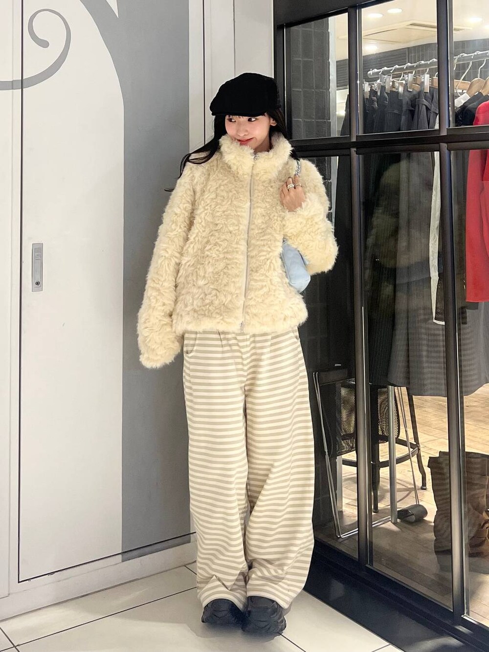 ホワイト系のブルゾン、ベージュ系のスウェットパンツ、ブルー系のショルダーバッグを着用したレディースの秋コーディネートの2枚目の写真
