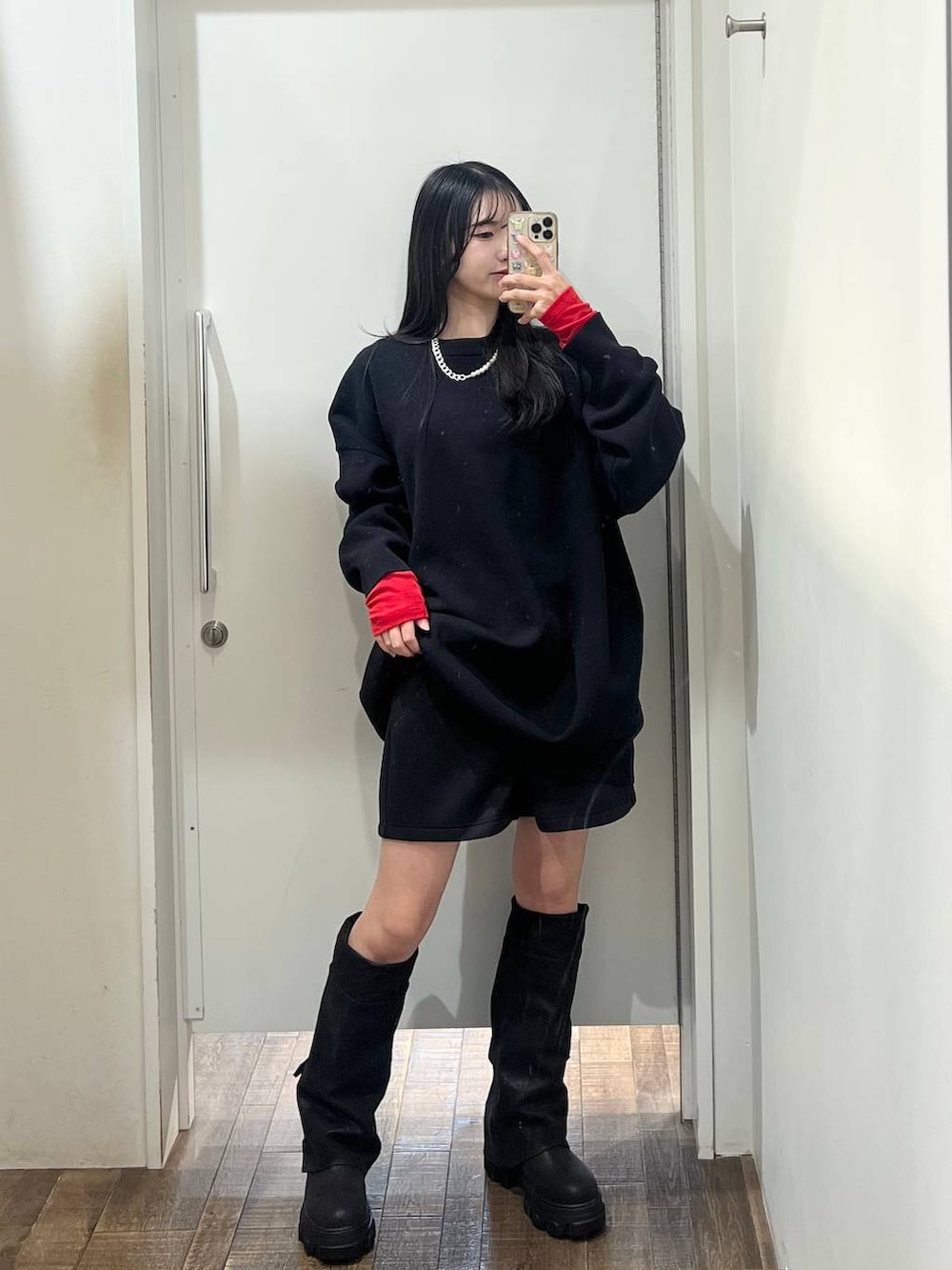 ブラック系のニット/セーター、ブラック系のブーツ、レッド系のTシャツ/カットソーを着用したレディースの冬コーディネートの2枚目の写真