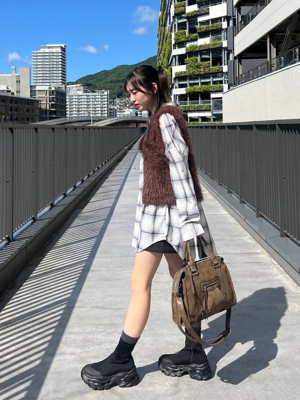 ブラウン系のベスト、ホワイト系のシャツ/ブラウス、ブラウン系のボストンバッグを着用したレディースの秋コーディネートの3枚目の写真