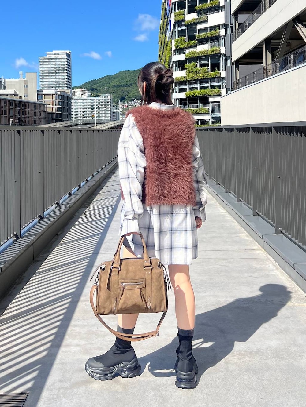 ブラウン系のベスト、ホワイト系のシャツ/ブラウス、ブラウン系のボストンバッグを着用したレディースの秋コーディネートの4枚目の写真