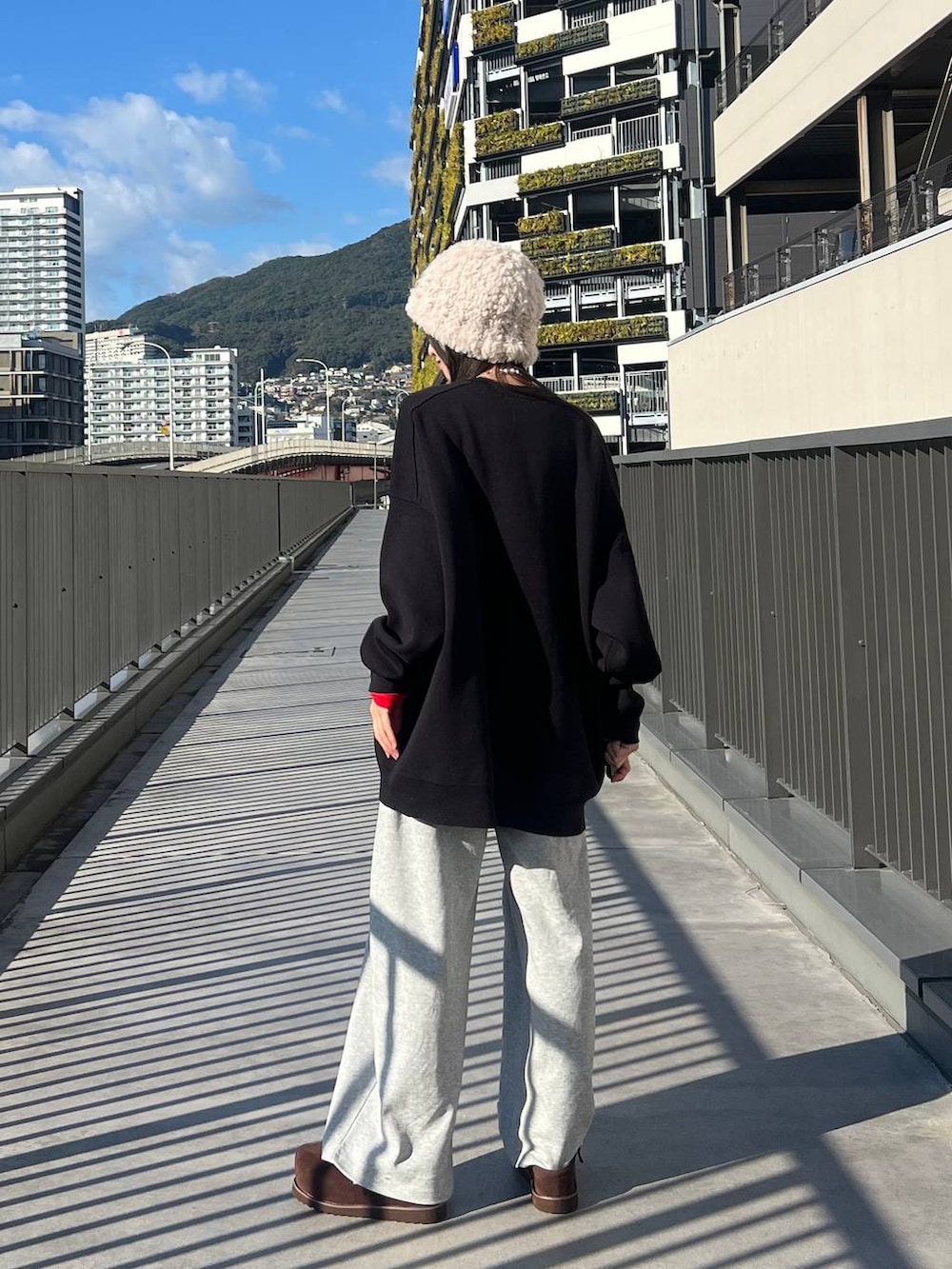 ブラック系のニット/セーター、ブラウン系のその他シューズ、グレー系のスウェットパンツを着用したレディースの冬コーディネートの6枚目の写真