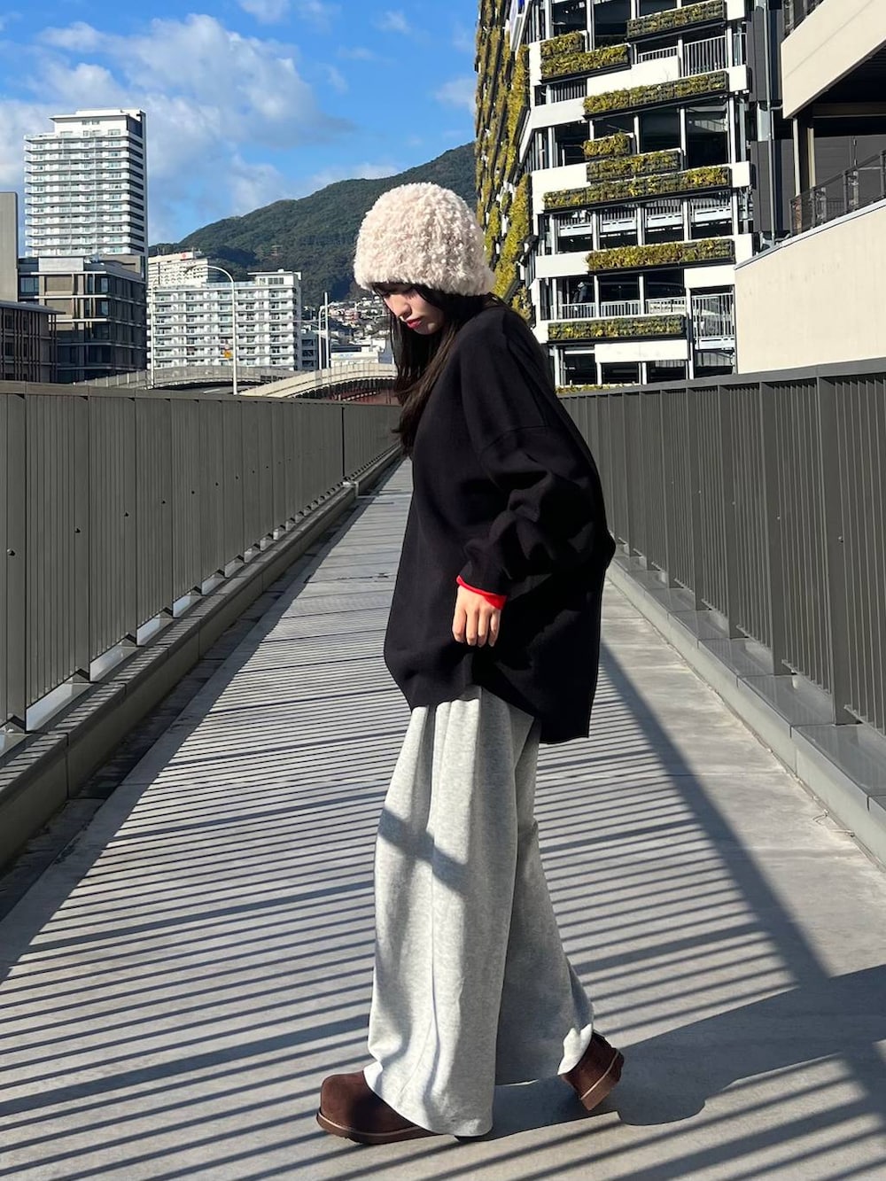 ブラック系のニット/セーター、ブラウン系のその他シューズ、グレー系のスウェットパンツを着用したレディースの冬コーディネートの3枚目の写真