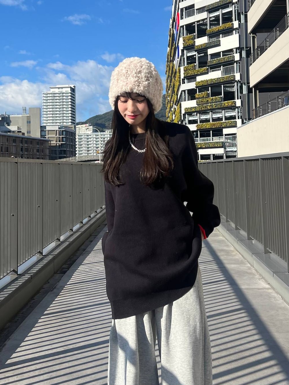 ブラック系のニット/セーター、ブラウン系のその他シューズ、グレー系のスウェットパンツを着用したレディースの冬コーディネートの2枚目の写真