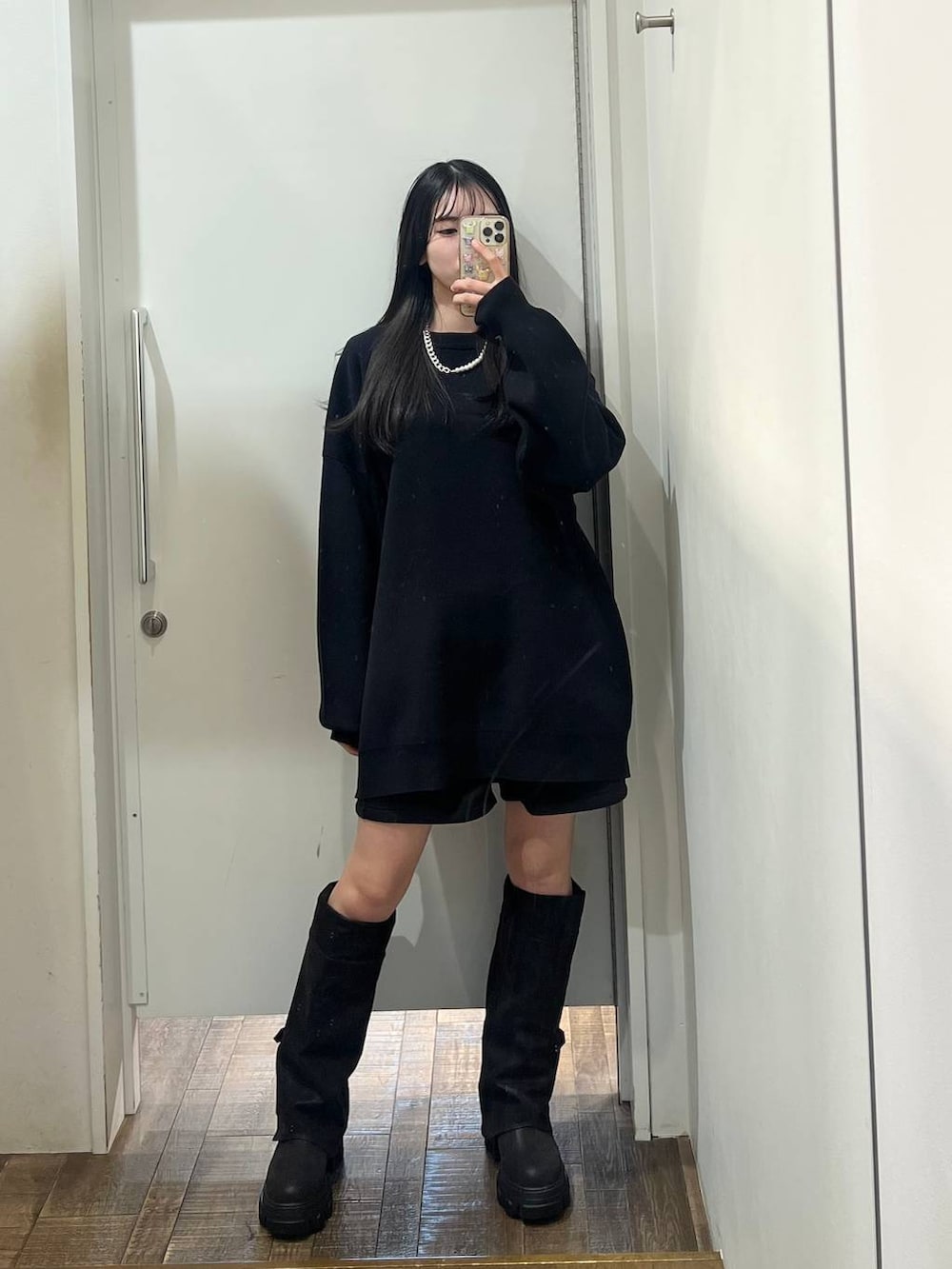 ブラック系のニット/セーター、ブラック系のブーツ、レッド系のTシャツ/カットソーを着用したレディースの冬コーディネートの3枚目の写真