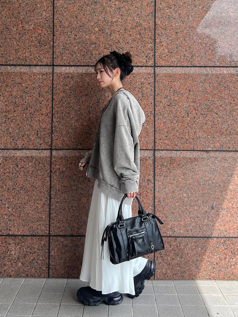 グレー系のパーカー、ブラック系のボストンバッグ、ブラック系のブーツを着用したレディースの夏コーディネートの2枚目の写真