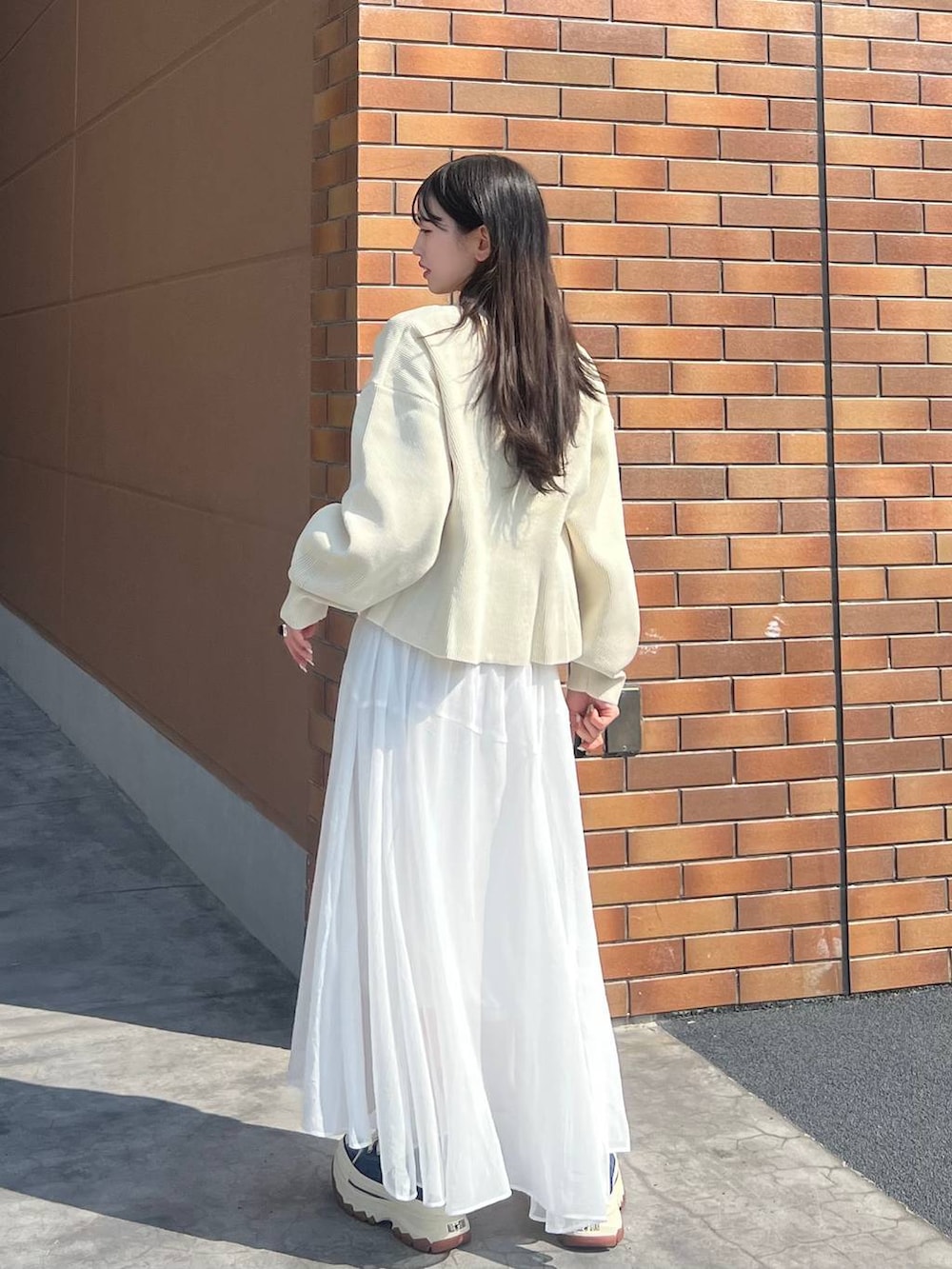 ブルー系のスニーカー、ホワイト系のカーディガン/ボレロ、ホワイト系のスカートを着用したレディースの春コーディネートの4枚目の写真