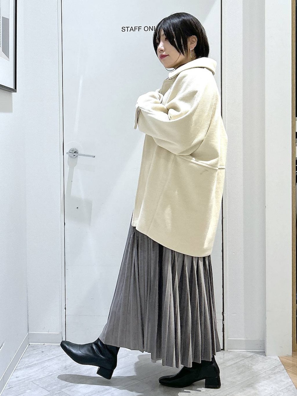 ブラック系のショルダーバッグ、グレー系のスカート、ブラック系のブーツを着用したレディースの秋コーディネートの3枚目の写真