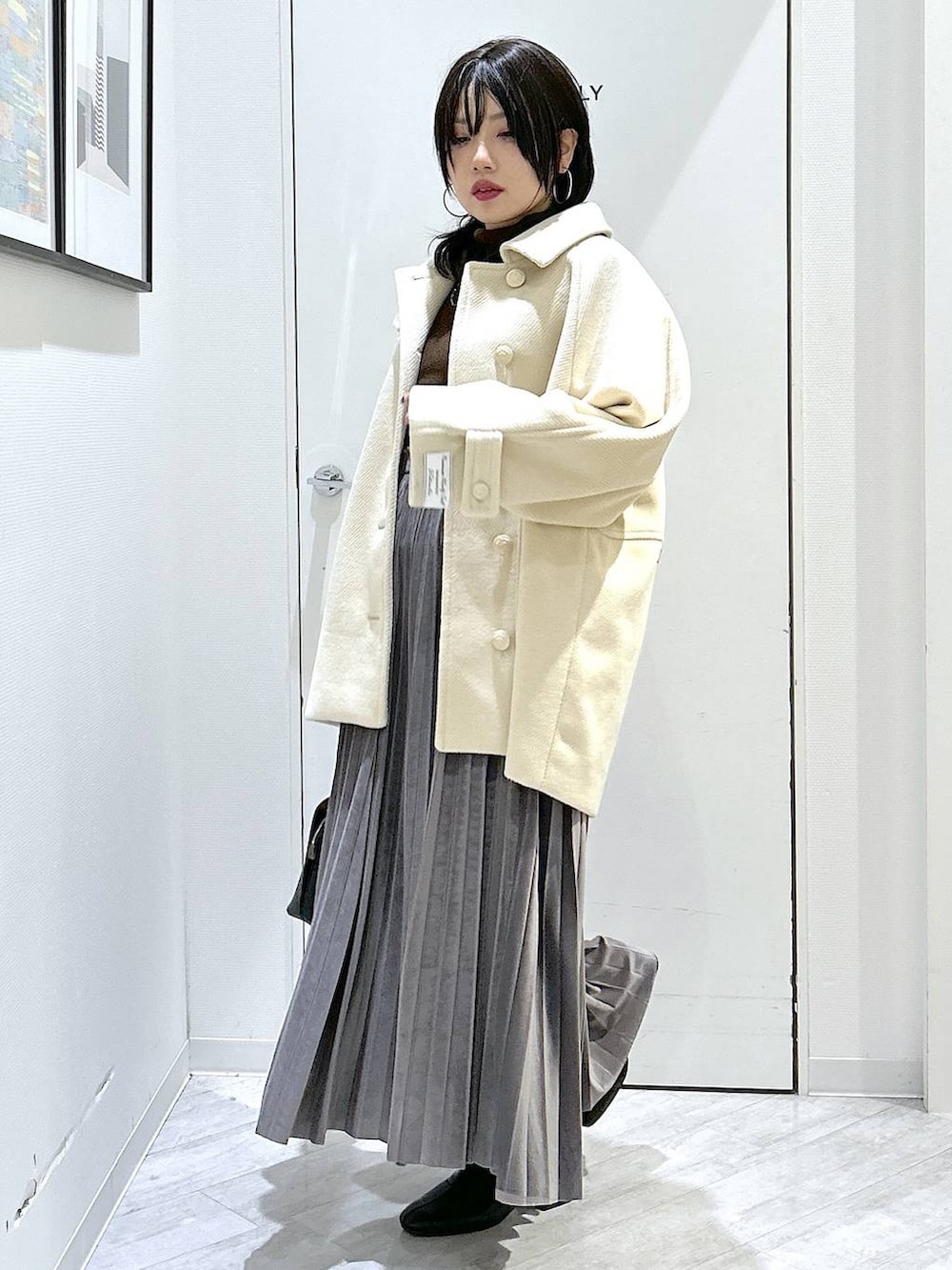 ブラック系のショルダーバッグ、グレー系のスカート、ブラック系のブーツを着用したレディースの秋コーディネートの2枚目の写真