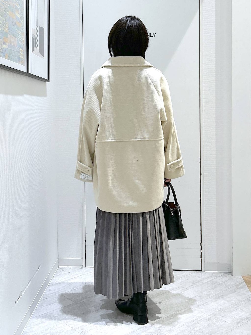 ブラック系のショルダーバッグ、グレー系のスカート、ブラック系のブーツを着用したレディースの秋コーディネートの5枚目の写真