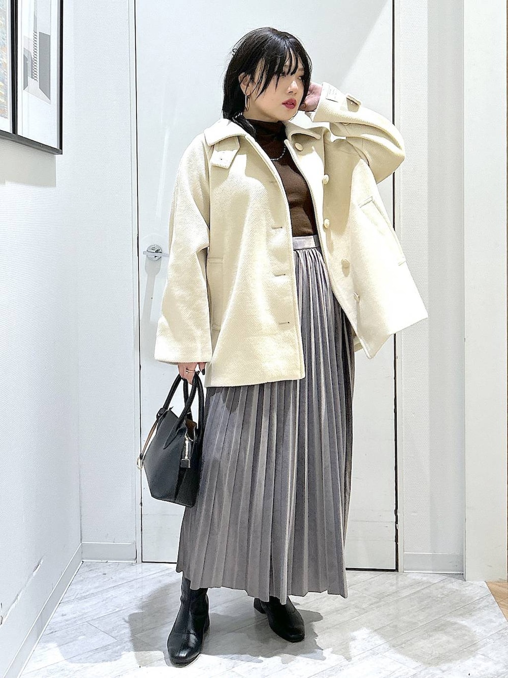 ブラック系のショルダーバッグ、グレー系のスカート、ブラック系のブーツを着用したレディースの秋コーディネートの8枚目の写真