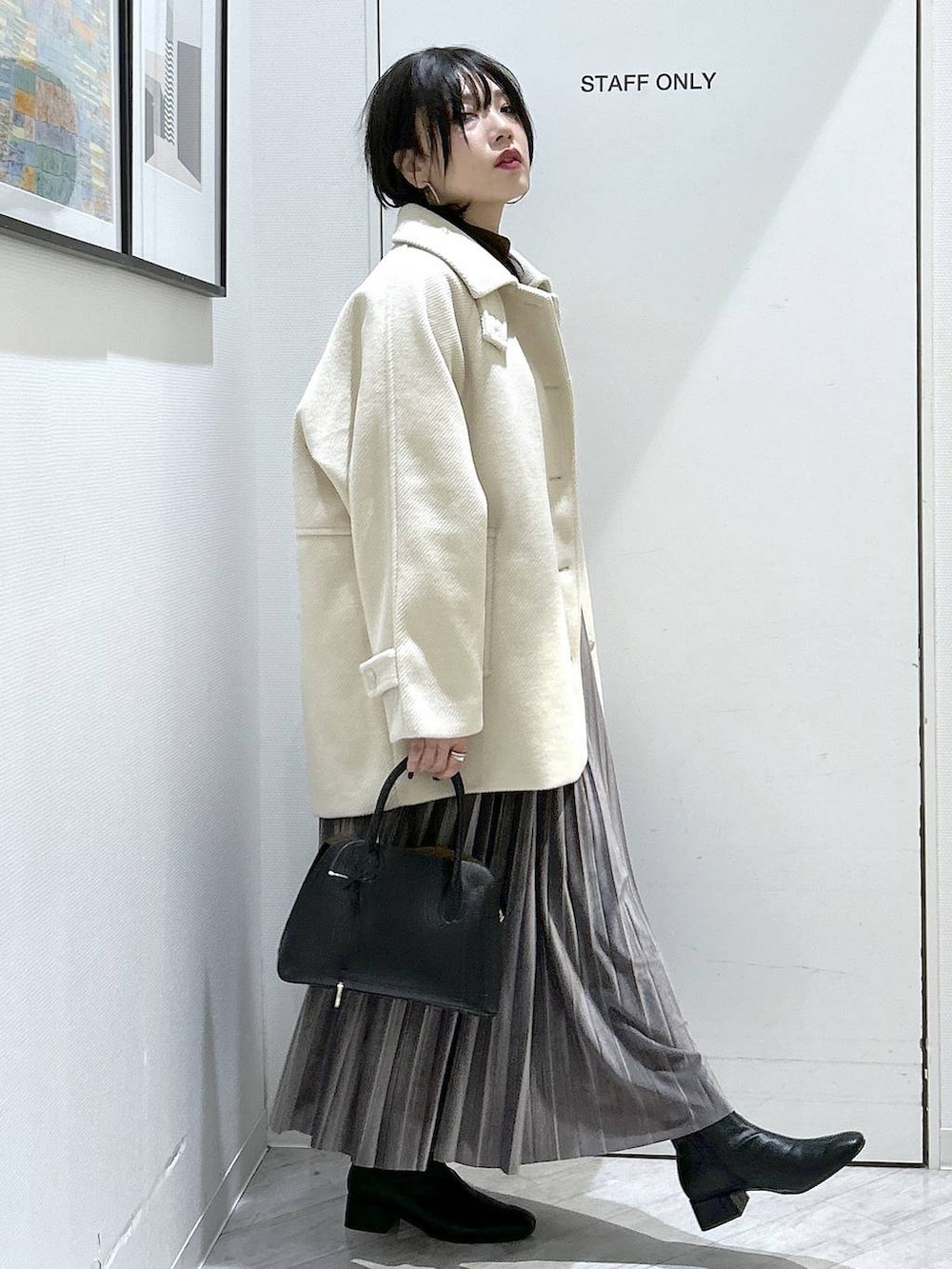 ブラック系のショルダーバッグ、グレー系のスカート、ブラック系のブーツを着用したレディースの秋コーディネートの7枚目の写真