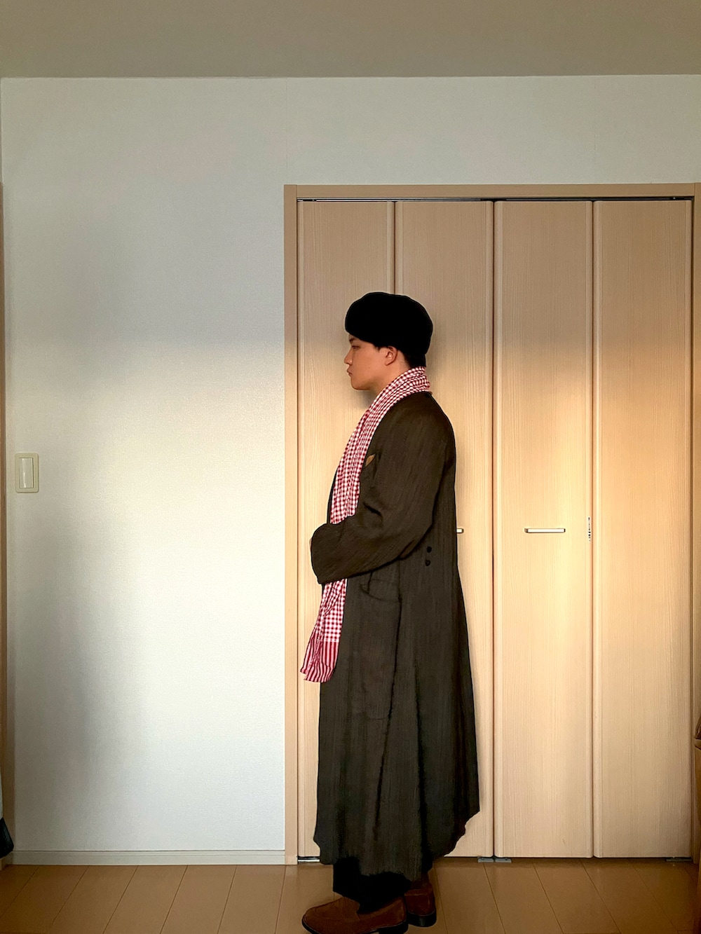 ブラウン系のローファー、ブラウン系のトレンチコート、レッド系のニット/セーターを着用したメンズの冬コーディネートの2枚目の写真