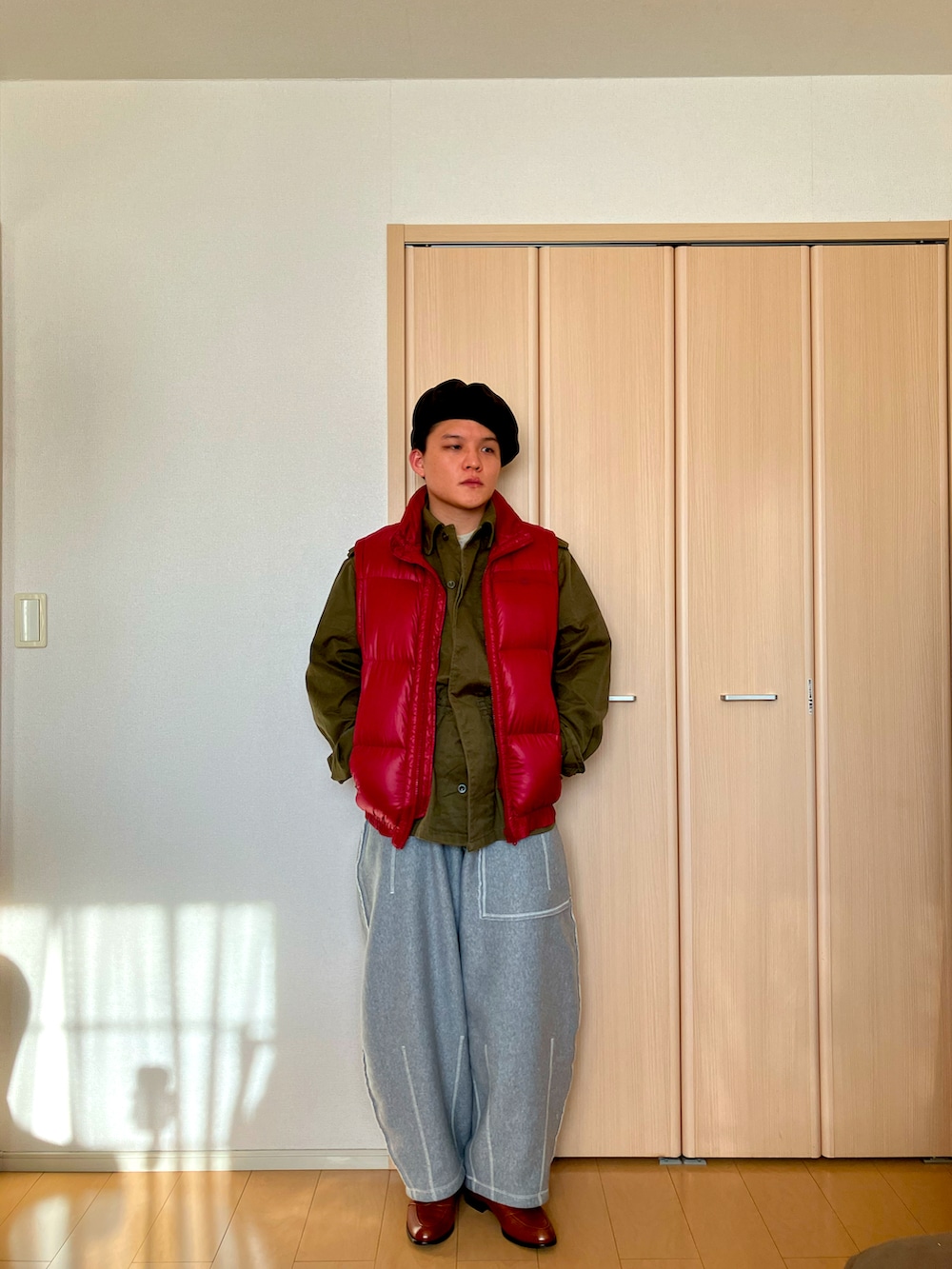 グレー系のスウェットパンツ、レッド系のダウンベスト、ブラウン系のローファーを着用したメンズの冬コーディネートの3枚目の写真