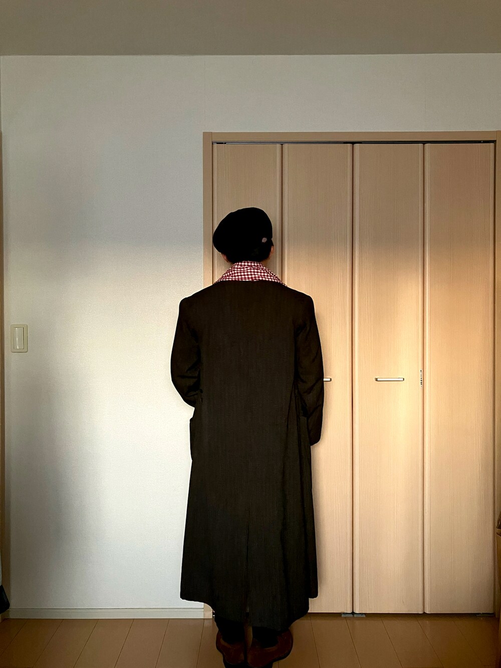 ブラウン系のローファー、ブラウン系のトレンチコート、レッド系のニット/セーターを着用したメンズの冬コーディネートの3枚目の写真