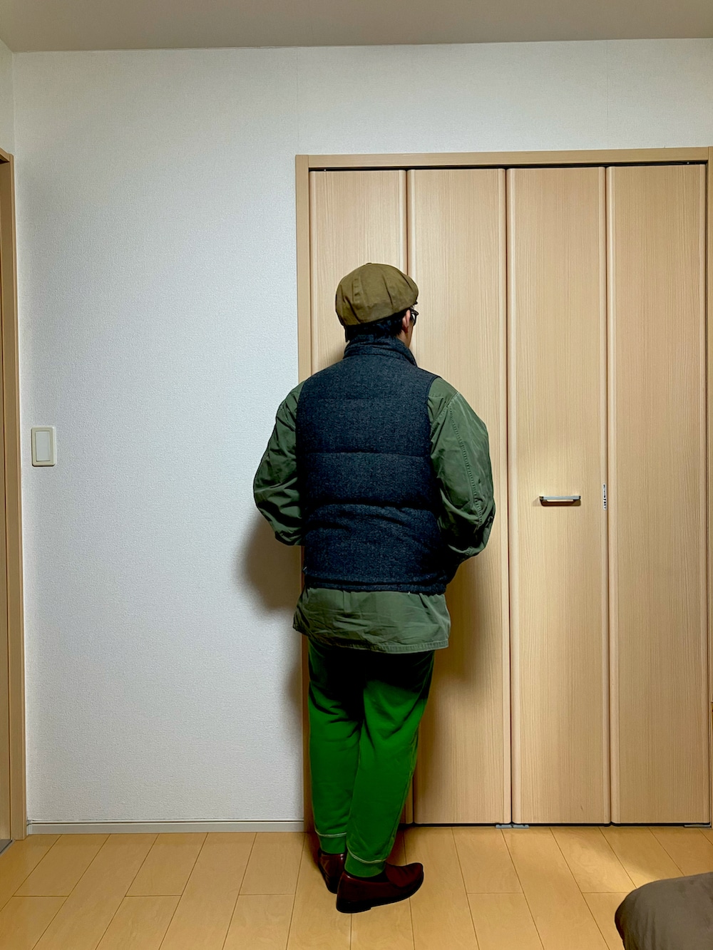 グリーン系のミリタリージャケット、グレー系のダウンベスト、グリーン系のスウェットパンツを着用したメンズの冬コーディネートの3枚目の写真